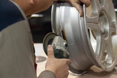 Tamirci bir değirmeni gibi özel bir araç elinde tutar, atölye döküm disk seviyeleri ve sonraki boyama için hazırlar