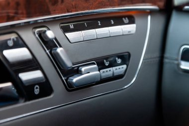 Otomatik koltuk hafıza düğmeleri beyaz işaret ve sembolleri ile çapraz olarak bir gri modern araba kontrol paneli ile kahverengi ve krom kaplama metal öğeleri yukarıdan aşağıya doğru yer alır.