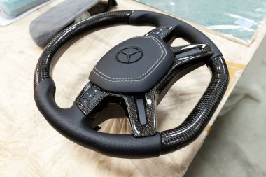 Novosibirsk, Rusya Federasyonu - 08.01.2018: atölye siyah bir araba direksiyon simidi sıkılır ve doğal deri ile delikli karbon yakın çekim Mercedes iz mat boya ile kaplı markası ile