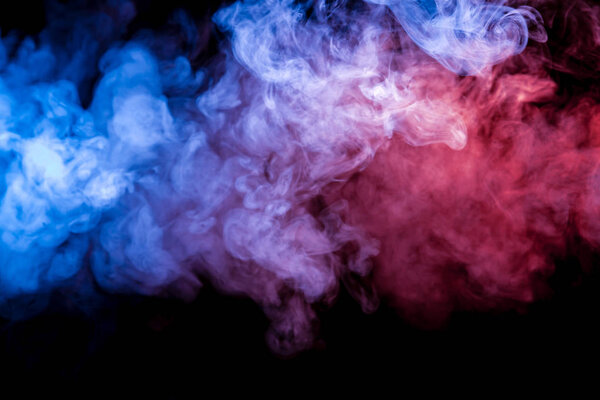 Multicolored heavy smoke from a vape of blue and purple color of the exhaled by scattered by clubs on a black isolated background. Bright clouds in the abstract form.