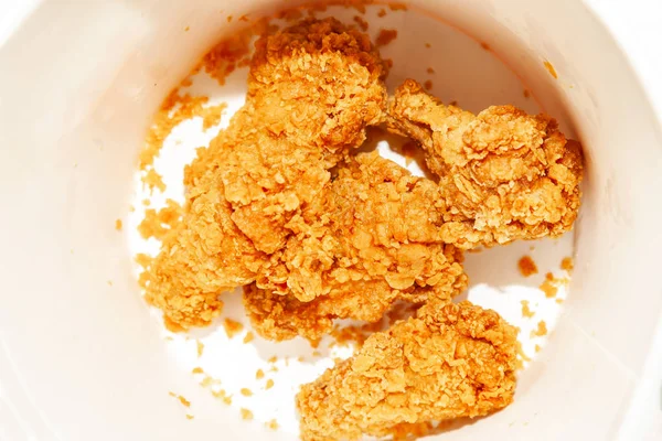 Close-up of appetizing fried chicken wings made from fresh meat at the bottom of a brown-breading bucket, a favorite fast-food for dinner and in the cinema.