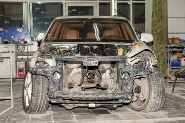 Atölye demonte beyaz araba tamir için hazırlanan: ön uç, kaput ve tampon iç donanımları, kaldırıldı ve yedek parçalar motor görünür.