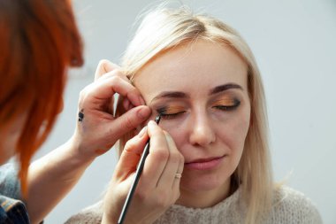 Makyaj sanatçısı düz bir kenar ile elinde bir fırça ile boya 