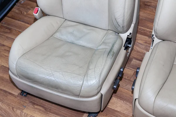 Velho assento de carro sujo cor bege de couro perfurado com rachaduras — Fotografia de Stock