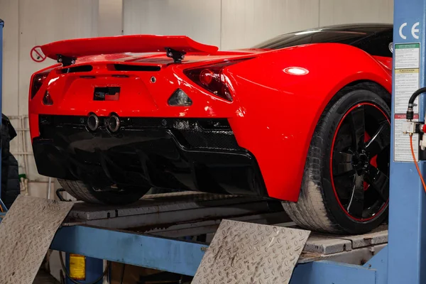 Red sports car raised on a lift in a car repair shop, rear bumpe — Stock Photo, Image