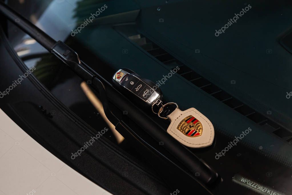 Novosibirsk, Russia - 08.01.2018: Car key remote door opener with a leather keychain from a Porsche Cayman lying on the windshield at the wipers