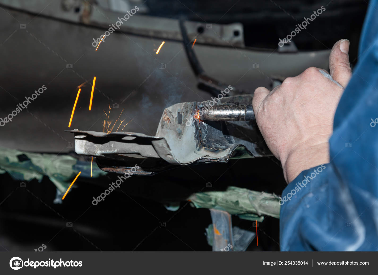 Close Up View Strong Man Is A Welder In Blue Working Overalls Wi
