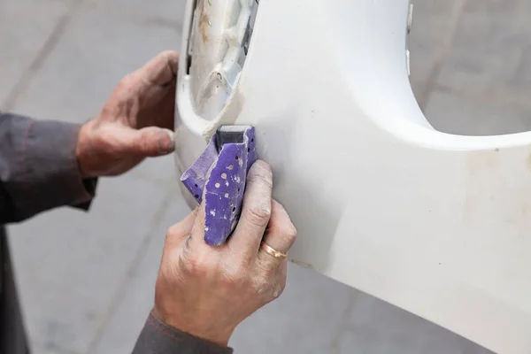 A man prepares a car body element for painting after an accident — Stock Photo, Image