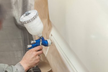 Bir erkek işçi boya tabancası ile araba vücut parçası boyar. 