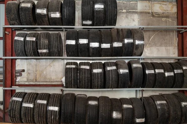 Un grand nombre de roues de voiture avec des pneus stockés verticalement dans rac — Photo