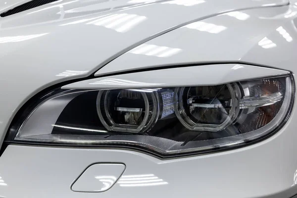 Front headlamp view of white used car stands in the auto showroo