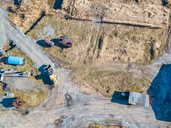 Aerial view of an excavator and yellow tractor transporting crus