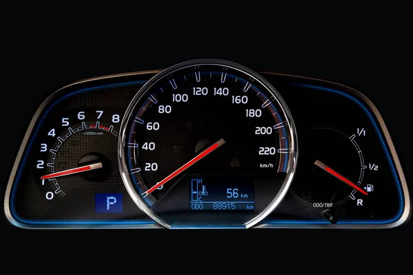 The dashboard of the car is glowing blue with red arrows at nigh