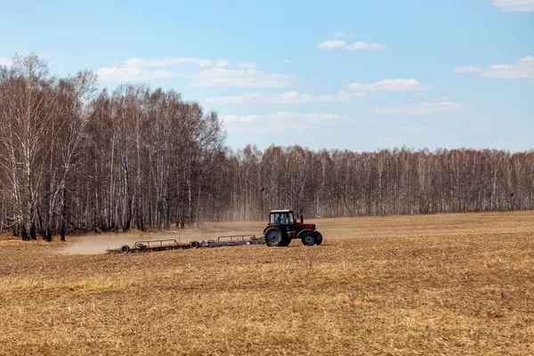 Czerwony Traktor z ciągniającym pługem do koszenia i pola — Zdjęcie stockowe