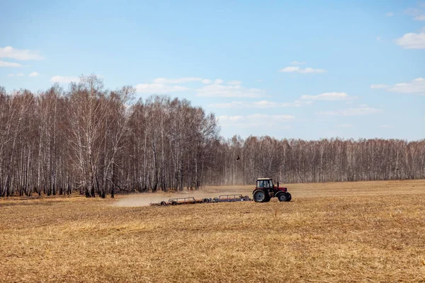 Czerwony Traktor z ciągniającym pługem do koszenia i pola — Zdjęcie stockowe