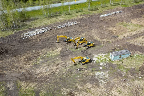 Vista lateral aérea de cuatro excavadoras de orugas amarillas de pie en g — Foto de Stock