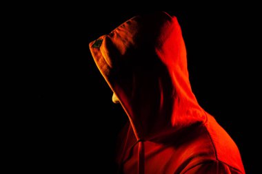 Yetişkin bir adam turuncu kapüşonlu sweatsh yan bakmak duruyor