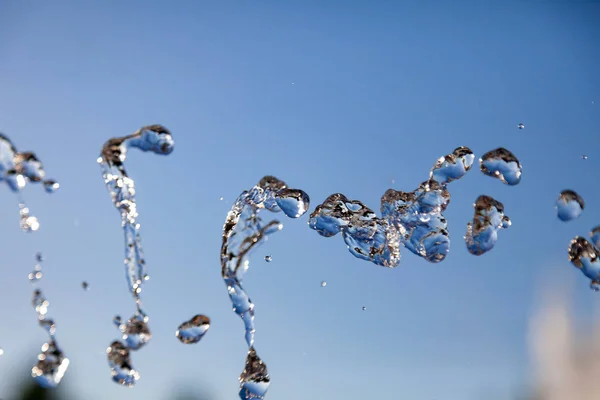 Water droplets frozen in the air with splashes and chain bubbles — Stock Photo, Image