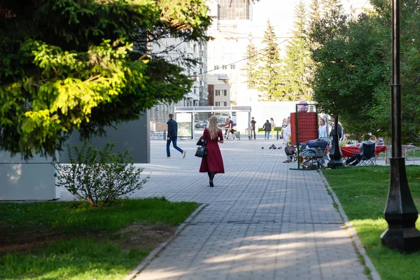 Дівчина в червоно-бордовий Довге плаття проходить через парк в — стокове фото
