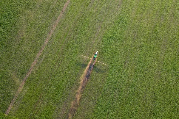 Vista aérea de un tractor de granja en un campo verde durante la pulverización de un — Foto de Stock