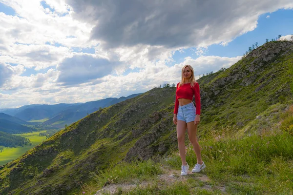 Dziewczyna w czerwonym szczycie i niebieskie szorty na skraju klifu w th — Zdjęcie stockowe