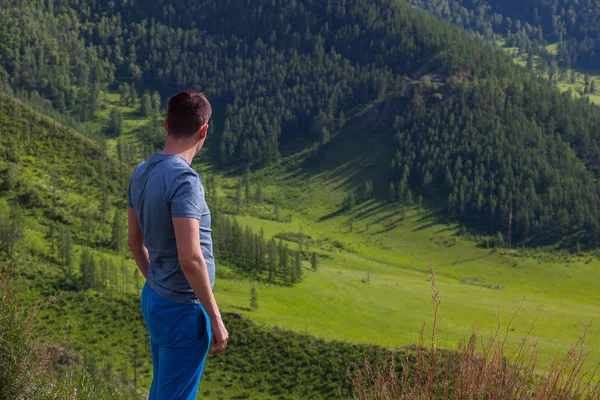 El tipo con una camiseta verde está de pie en el borde del acantilado en — Foto de Stock