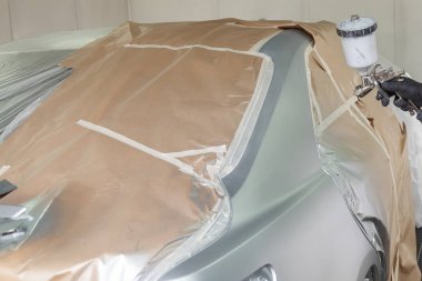 Bir erkek işçi boya tabancası ile araba vücut parçası boyar. 