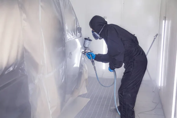 Un operaio in tuta e guanti blu dipinge con uno spray gu — Foto Stock