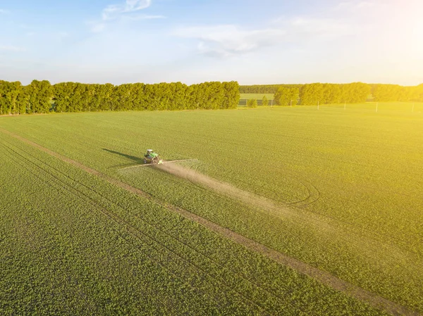 Püskürtme sırasında yeşil bir alanda bir çiftlik traktörünün havadan görünümü