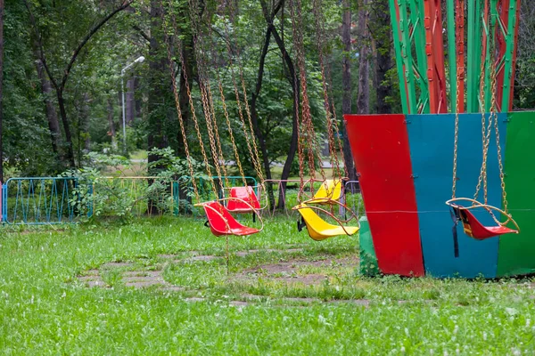 Sedili in plastica multicolore gialla e rossa appesi alle catene — Foto Stock