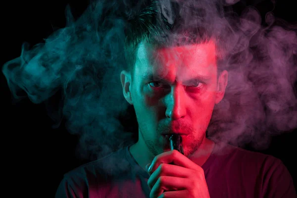 Een man houdt in zijn hand en sleept op een elektronische sigaret wit — Stockfoto