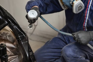 Tulum ve eldiven bir erkek işçi bir sprey tabancası ile boya bir f