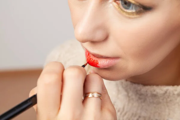 Primer plano aplicando en los labios, el maquillador sostiene un pincel — Foto de Stock