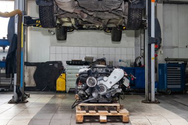 Yükseltilmiş otomobilin altına monte edilmiş bir palette kullanılan yedek motor 