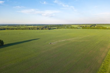 Püskürtme sırasında yeşil bir alanda bir çiftlik traktörünün havadan görünümü