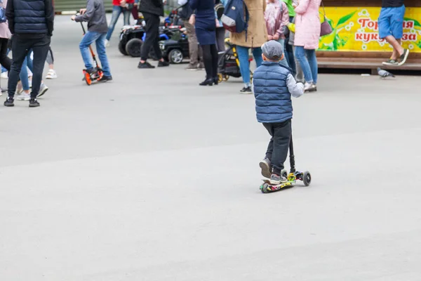 Egy fiú egy kupakot roll a robogók nyomja le az út SMIL — Stock Fotó