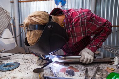 Damalı kırmızı gömlek li genç adam kaynak paslanmaz bir stee