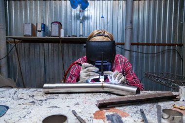 Damalı kırmızı gömlek li genç adam kaynak paslanmaz bir stee