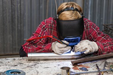 Damalı kırmızı gömlek li genç adam kaynak paslanmaz bir stee