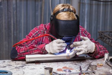 Damalı kırmızı gömlek li genç adam kaynak paslanmaz bir stee