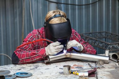 Damalı kırmızı gömlek li genç adam kaynak paslanmaz bir stee