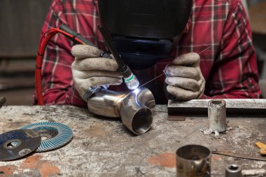 Damalı kırmızı gömlek li genç adam kaynak paslanmaz bir stee