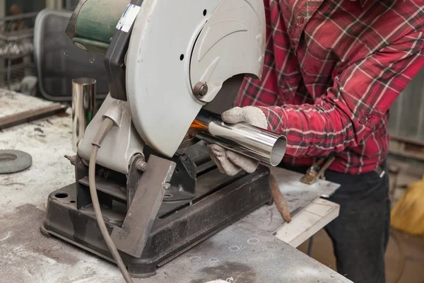 Een mannelijke werknemer snijdt een roestvrijstalen pijp op een speciale machine f — Stockfoto