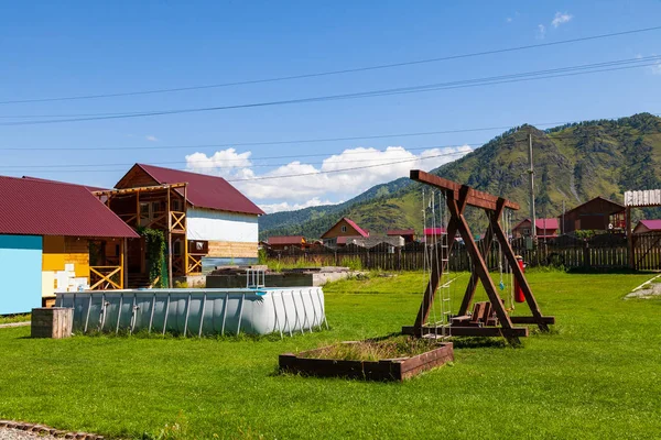 Ahşaptan yapılmış büyük bir salıncak ve bir gr üzerinde şişme kauçuk havuz — Stok fotoğraf