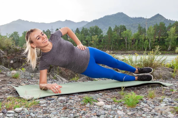 Blonde schöne Mädchen lächelt und macht ein Warm-up liegend auf der s — Stockfoto