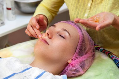 Deneyimli bir kozmetolojist f emülsiyon maskesi uygular