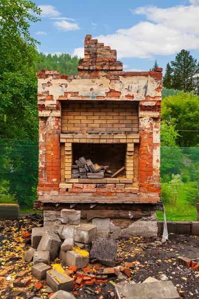 Old poor destroyed fireplace standing on the street with firewoo