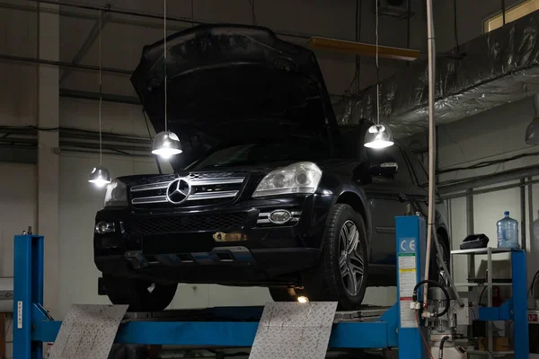 Used black car Mercedes Benz GL with an open hood raised on a fo — Stock Photo, Image