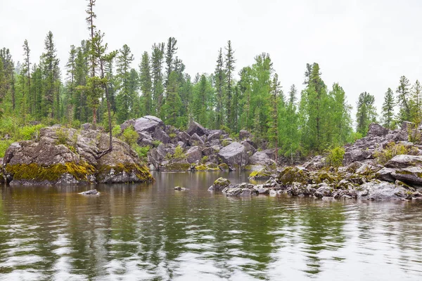 Stony shore of the lake with a creek on the Teletskoye lake in t