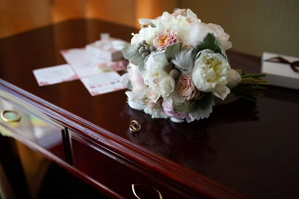Wedding bouquet of peonies and roses lying on a wooden vintage t